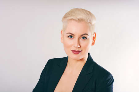 Business portrait of beautiful mature woman wearing jacket, posing on grey background, short haircutの写真素材