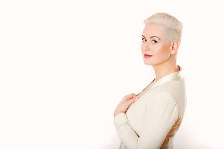 Studio portrait of beautiful mature woman on white background, looking over her shoulder, wearing jacket, short haircutの写真素材