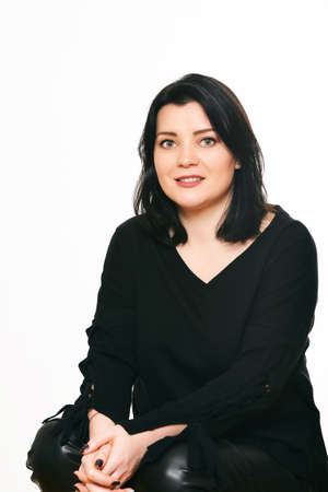 Studio portrait of mature woman posing on white background, sitting on chair, wearing black clothesの写真素材