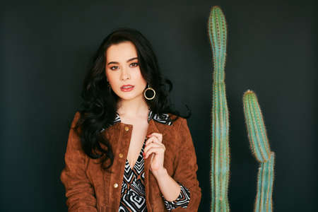 Fashion portrait of stylish young woman with volume hairstyle, wearing brown leather jacket