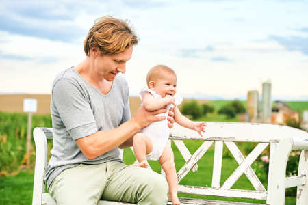 Happy young father playing with baby girl in beautiful summer parkの写真素材
