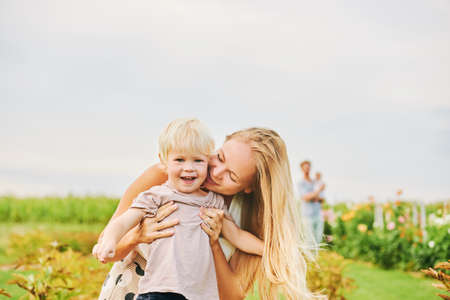 Outdoor portrait of happy young mother playing with toddler son in garden, family lifestyleの写真素材
