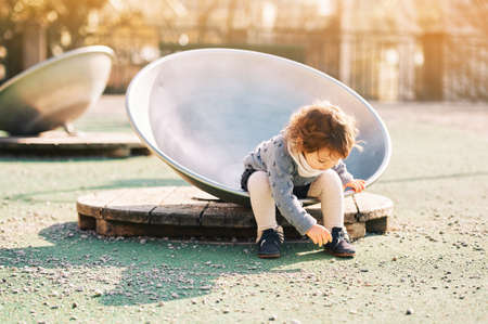 Outdoor portrait of adorable toddler girl having fun on playground, 1 - 2 year old kid playing in parkの写真素材