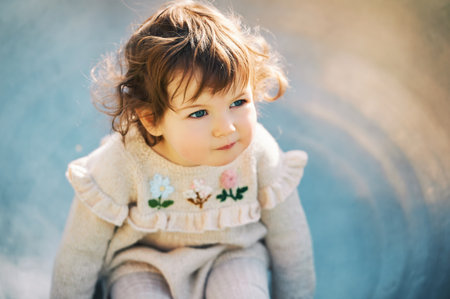 Outdoor close up portrait of adorable toddler girl having fun on playground, 1 - 2 year old kid playing in parkの写真素材