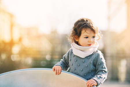 Outdoor portrait of adorable toddler girl having fun on playground, 1 - 2 year old kid playing in parkの写真素材