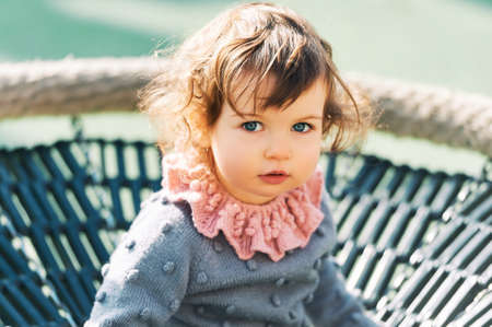 Outdoor portrait of adorable toddler girl having fun on playground, 1 - 2 year old kid playing in parkの写真素材