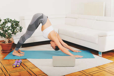 Young fit woman working out at home in living room, online sport trainingの写真素材