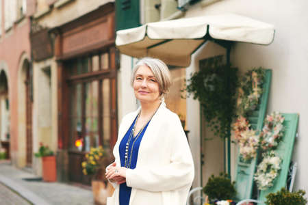 Fashion portrait of beautiful and elegant middle age woman posing outside