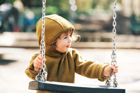 Outdoor portrait of cute toddler kid having fun on playground, wearing warm jumpsuitの写真素材