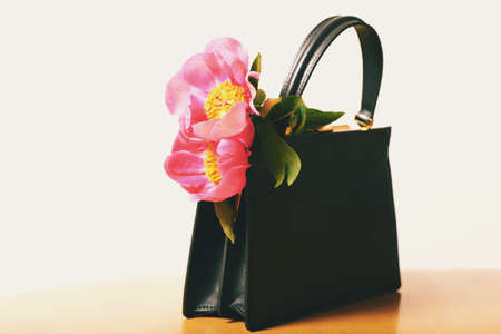 Small black leather bag with pink peony flowersの写真素材