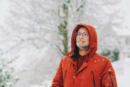 Outdoor portrait of middle age man, 55 - 60 years old, enjoying nice cold day, wearing red orange winter jacketの写真素材