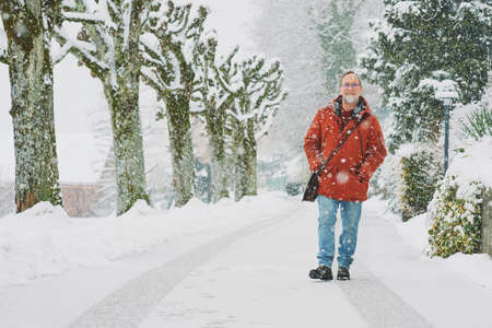 Outdoor portrait of middle age man, 55 - 60 years old, enjoying nice cold day, wearing red orange winter jacketの写真素材