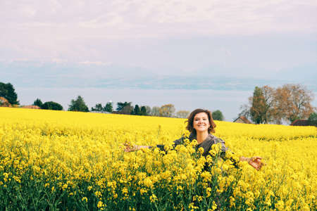 Outdoor portrait of happy young woman posing in yellow colza flowers