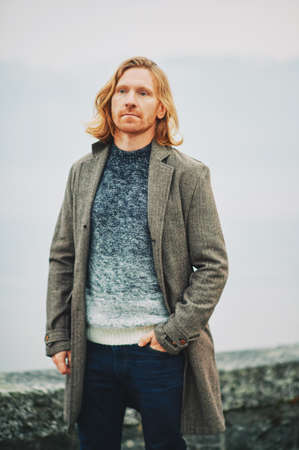 Outdoor portrait of young red haired man, wearing pullover and coat, cold foggy dayの写真素材