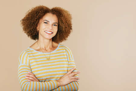 Studio portrait of beautiful middle age woman isolated on beige background, wearing grey and yellow...
