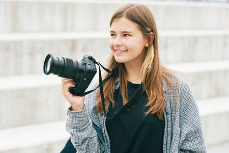 Outdoor portrait of young happy teenage girl holding mirrorless cameraの写真素材