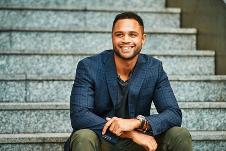 Outdoor urban portrait of African American male model sitting on stairs