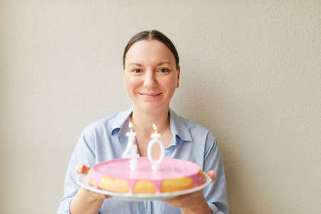 Happy middle age 40 year old woman holding cake with candlesの写真素材