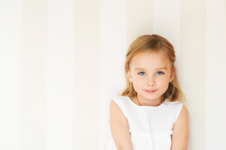 Portrait of adorable little girl with blue eyes wearing white dressの写真素材