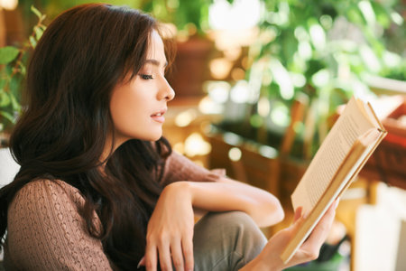 Portrait of young woman reading book on balconyの写真素材
