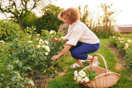 Outdoor portrait of beautiful 50 year old woman enjoying nice day in flower park or garden, happy...