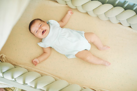 Little crying 6 months old baby lying in a crib, top viewの写真素材