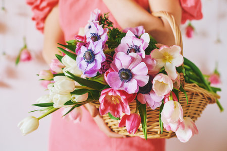 Woman holding basket with many colorful flowers, spring backgroundの写真素材