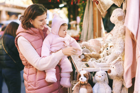 Happy young mother with adorable little baby visiting Christmas marketの写真素材