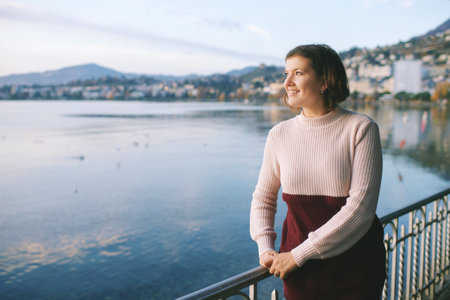 Outdoor portrait of beautiful young woman relaxing by mountain lake, cold weatherの写真素材