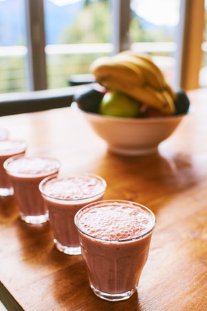 Homemade fruit milkshake, a few glasses in a row placed on wooden tableの写真素材