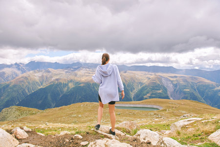 Outdoor portrait of happy young woman hiking in autumn mountains, back viewの写真素材