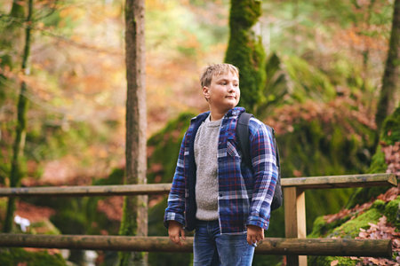 Outdoor portrait of happy kid boy hiking in autumn forest, wearing backpackの写真素材
