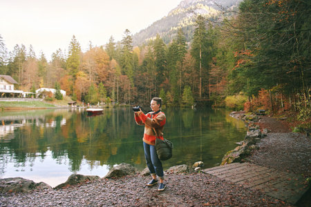 Outdoor portrait of happy middle age woman taking pictures by the lake, travel and active lifestyle conceptの写真素材
