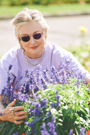 Outdoor portrait of happy senior woman enjoying nice day in summer garden
