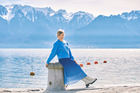 Outdoor fashion portrait of happy mature woman posing by the lake, wearing blue pullover and skirtの写真素材