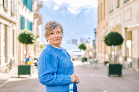 Outdoor portrait of beautiful middle age 55 - 60 year old woman posing outside, wearing blue pulloverの写真素材