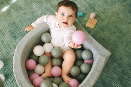 Adorable baby girl playing with mini ball pit, fun and activities for little kidsの写真素材