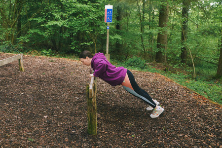 Outdoor portrait of happy middle age woman exercising with wooden equipment in spring forest, active and healthy lifestyleの写真素材