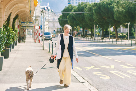 Outdoor portrait of happy mature woman walking with labrodoodlee dogの写真素材