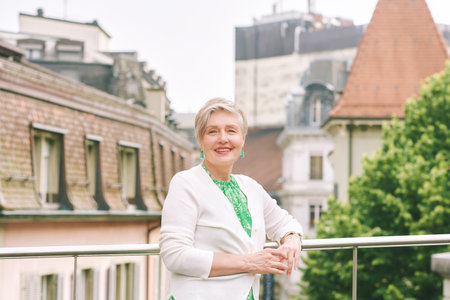 Outdoor portrait of beautiful 55 -60 year old woman posing with city background, fashion and healthy lifestyleの写真素材