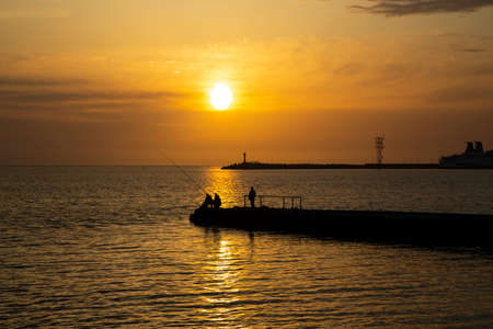 Fishing on the sea. Men fish in the evening at sunset in summerの写真素材