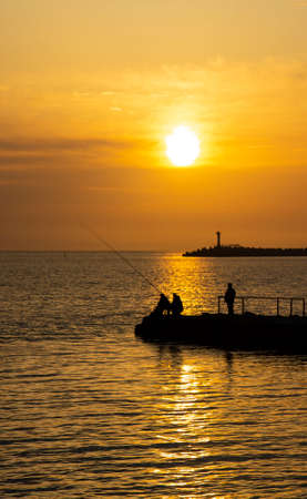 Fishing on the sea. Men fish in the evening at sunset in summerの写真素材