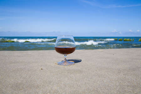 Cognac in a glass on the shore of the blue sea. Stay with alcohol in the Southの写真素材
