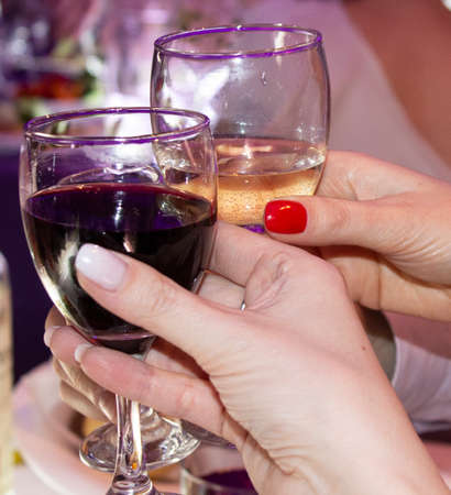 Glasses of red and white wine in the hands of women. Christmas, New year, Friday, meeting friendsの写真素材