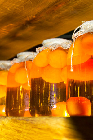 A jar of peaches on a dark background. Canned fruit in large glass jars on a wooden shelfの写真素材