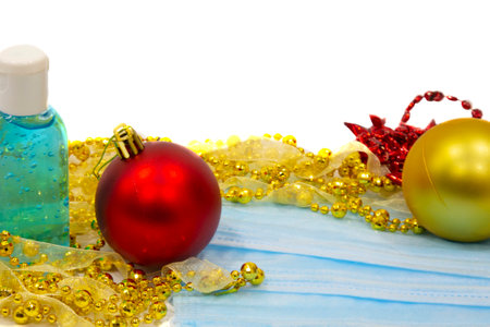 blue medical mask next to Christmas decorations on a white background. Christmas trees, balloons, New year's mood and respiratory protectionの写真素材