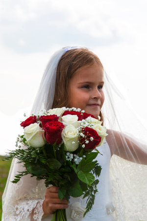 little girl in a bride's dress  a veil and a wedding bouquet. Beauty.の写真素材