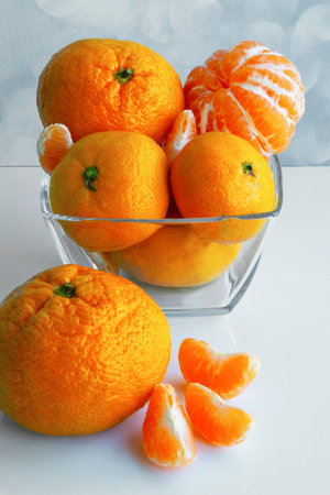 Mandarine orange or tangerine on a white table. Tangerines in a glass bowl. Tangerine slicesの写真素材
