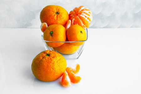 Mandarine orange or tangerine on a white table. Tangerines in a glass bowl. Tangerine slicesの写真素材