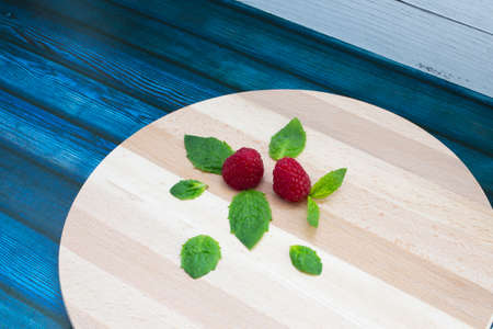 Fresh raspberries and mint on a wooden table. Ripe red raspberries and green peppermint leaves on a wooden standの写真素材